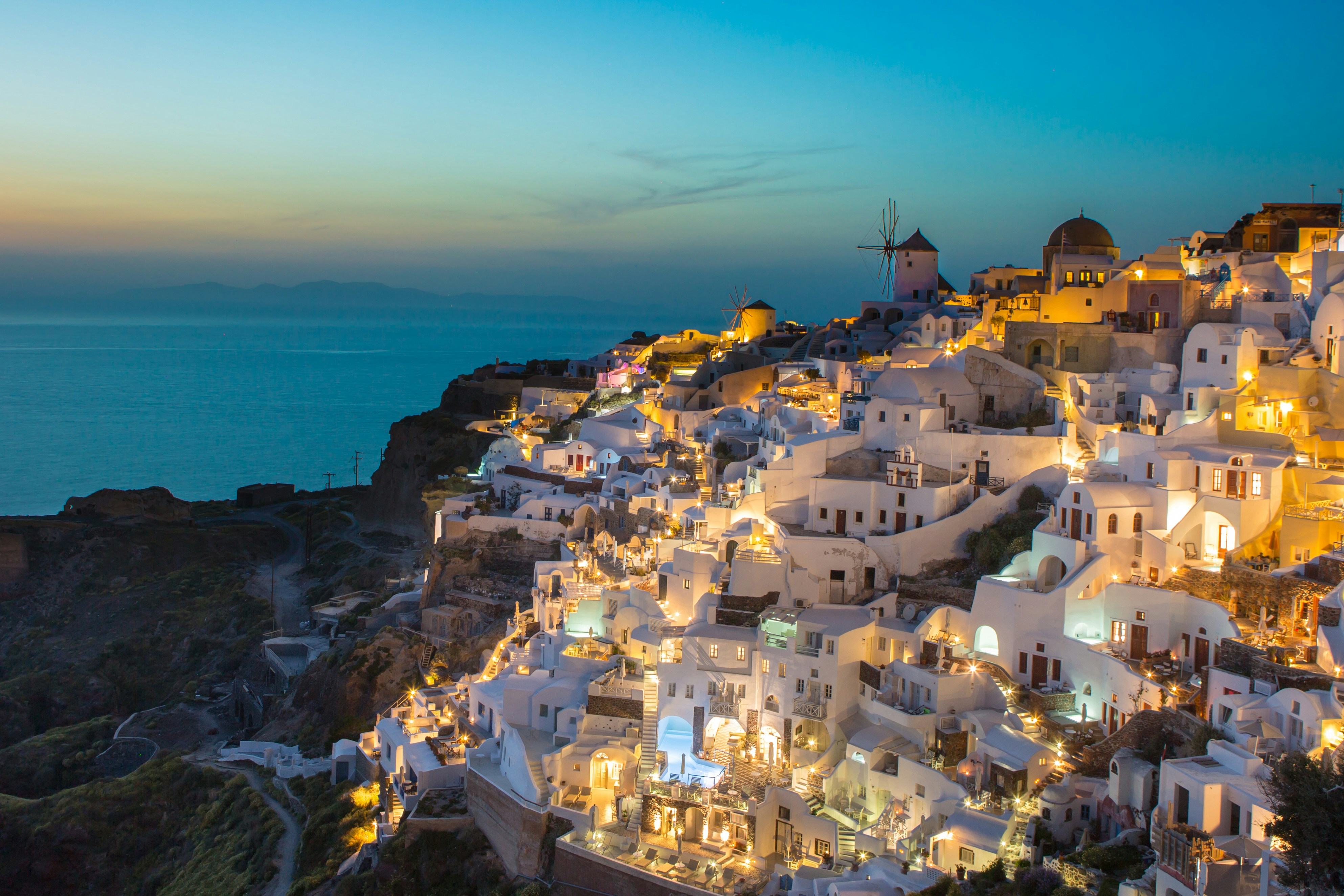 Whitewashed village of Oia, Santorini, glowing at dusk above the Aegean